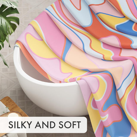 Colorful fabric draped over a white bowl with a plant and wooden board in the background, labeled 'SILKY AND SOFT'.