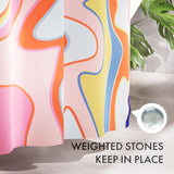 Colorful abstract shower curtain with text 'Weighted Stones Keep in Place' on a bathroom floor.