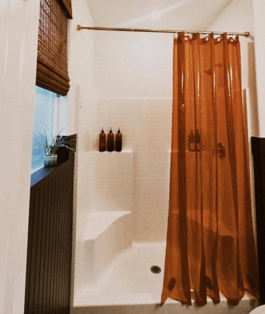 Orange translucent shower curtain in a white tiled bathroom