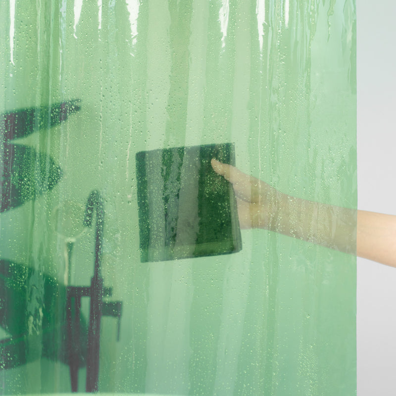 Person cleaning a shower curtain liner with a towel against a bathroom background