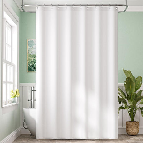 White shower curtain in a bathroom with green walls, a plant, and a bathtub.