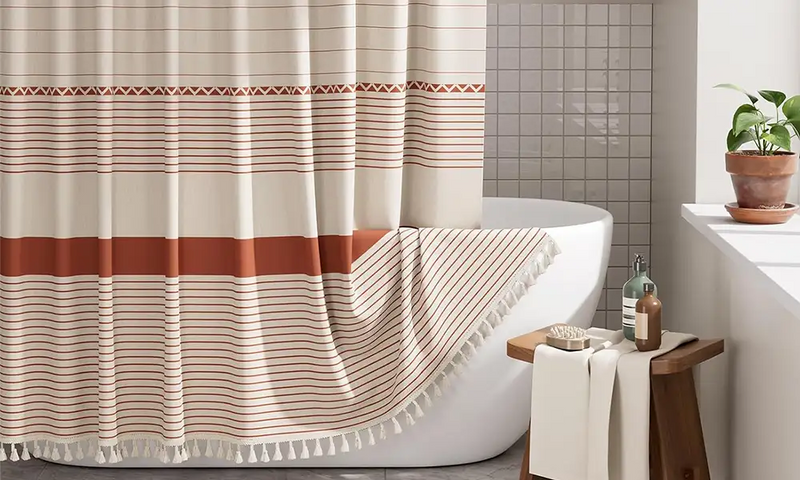 AmazerBath farmhouse striped shower curtain with warm neutral bands and tassel trim beside a bathtub