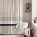 Bathroom with a striped shower curtain, bathtub, and wooden stool.