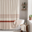 Bathroom with a striped shower curtain, bathtub, and wooden stool.