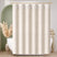 Beige striped shower curtain in a bathroom with a bathtub and decorative elements.
