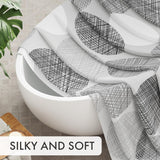 White bathtub with black geometric patterned towel draped over it, with text 'SILKY AND SOFT' at the bottom.