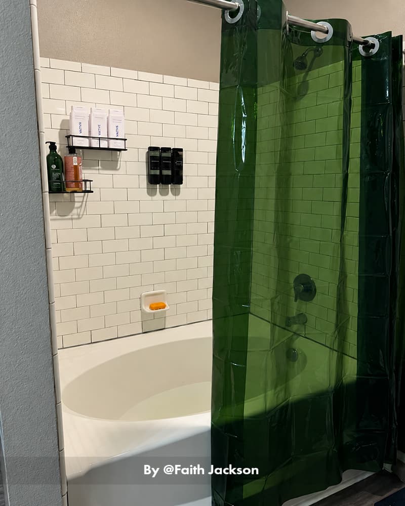 AmazerBath emerald hookless Sun EVA shower curtain liner hanging beside a white bathtub in a tiled bathroom.