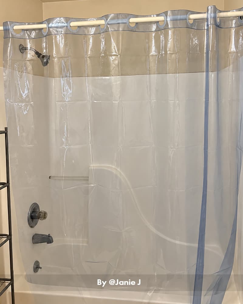 AmazerBath clear hookless Sun EVA shower curtain liner with blue trim hanging around a white bathtub and shower.