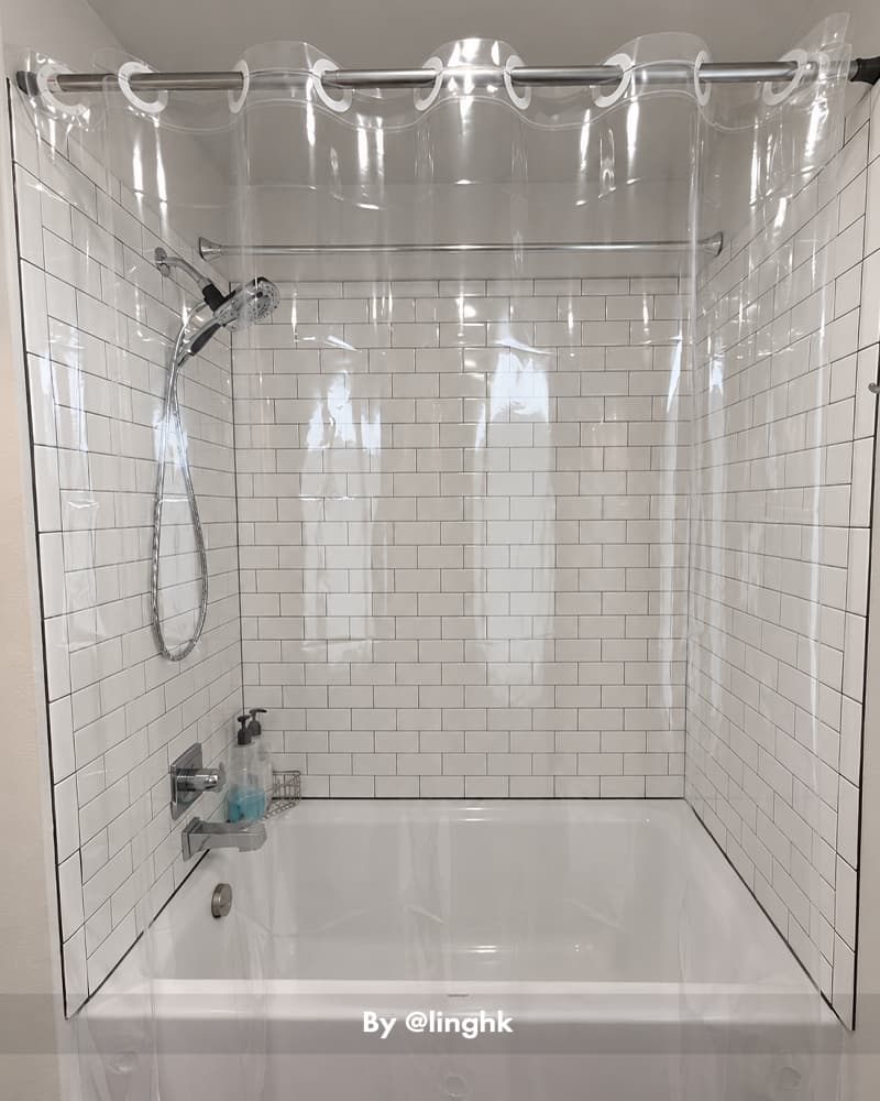 AmazerBath clear hookless Sun EVA shower curtain liner enclosing a white subway-tile bathtub and shower.