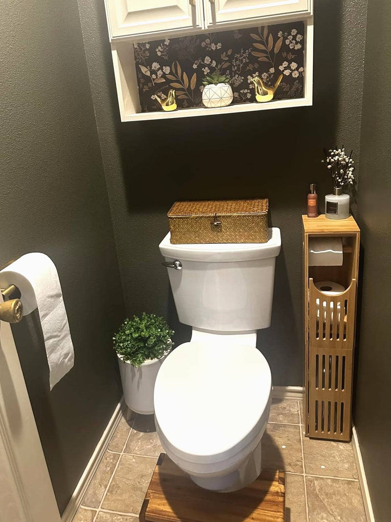 Bathroom with toilet, decorative elements, and a small shelf.