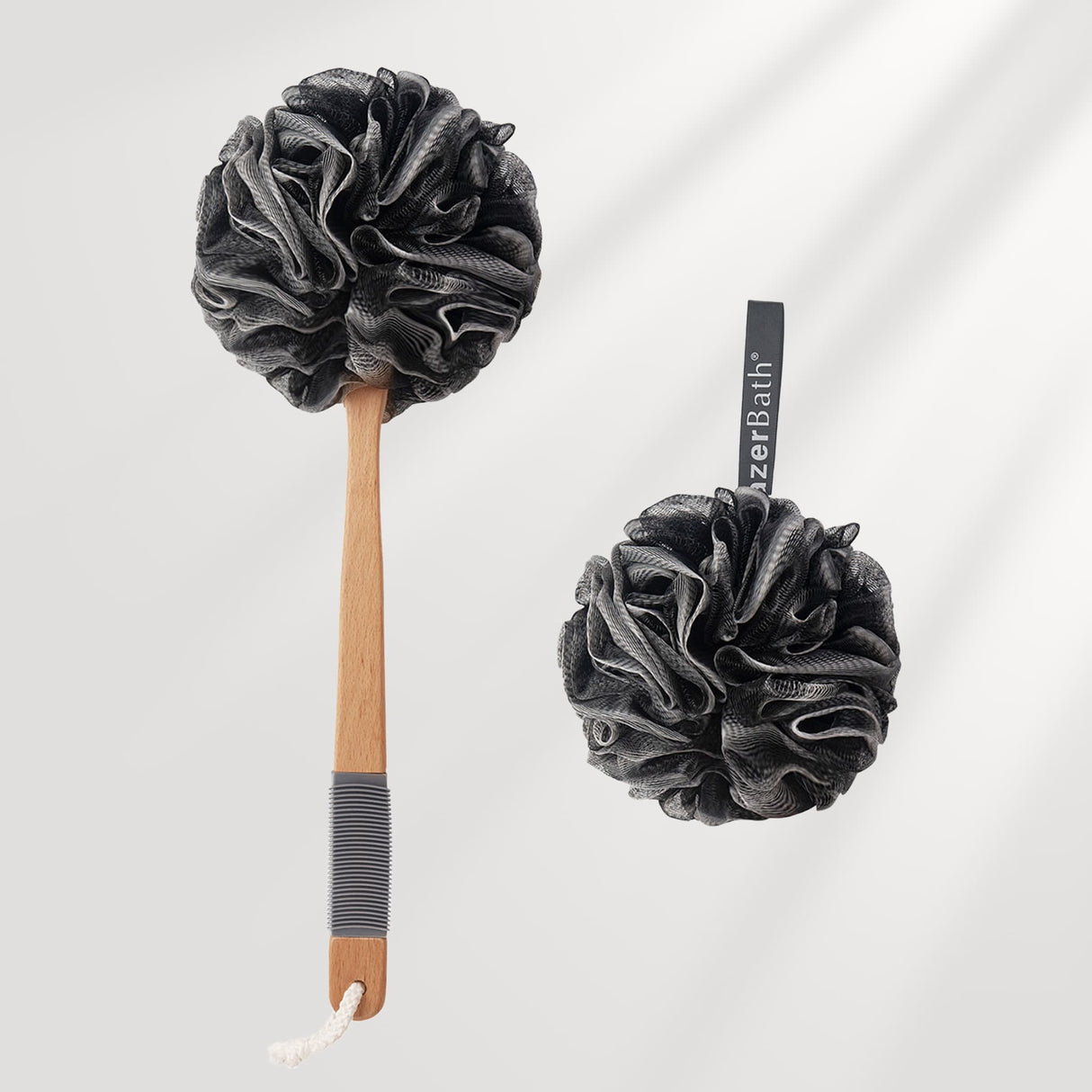 Two black bath pouf scrubbers with wooden handles on a light gray background