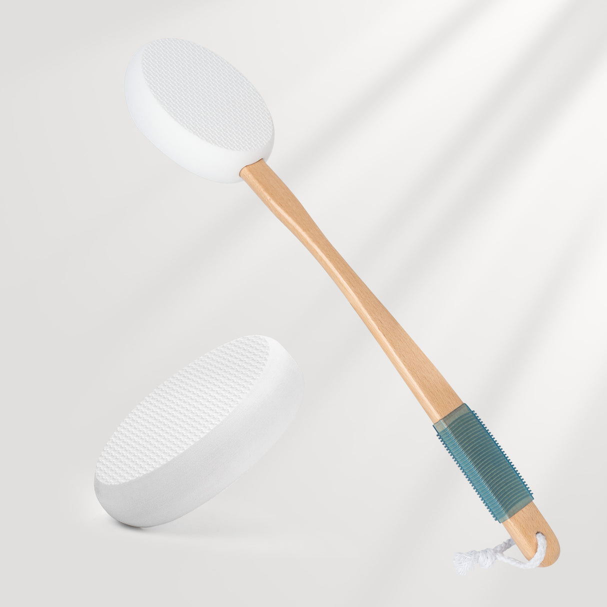 White spatula with wooden handle and blue silicone end on a light gray background