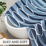 Blue and white patterned blanket draped over a white chair with a plant in the background.