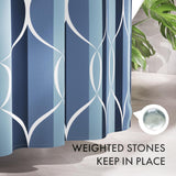 Blue and white patterned shower curtain with a small container of weighted stones on a bathroom floor.