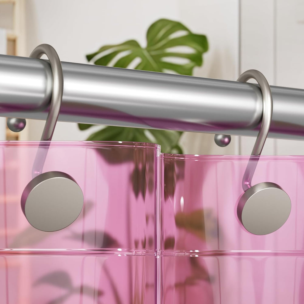 Pink shower curtain with silver rings and a plant in the background