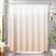 Beige gradient shower curtain in a bathroom setting with plants and a mirror.
