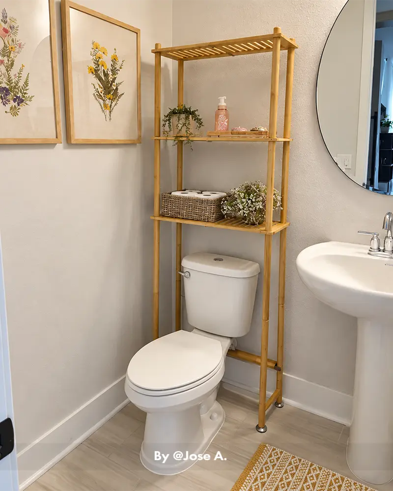 AmazerBath over-the-toilet storage rack in natural bamboo, shown organizing bathroom supplies in a real home setting
