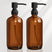 Two brown glass bottles with black pumps on a white background