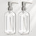 Two clear glass bottles with silver pump dispensers on a light gray background
