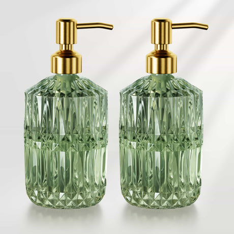 Two green glass soap dispensers with gold pumps on a white background