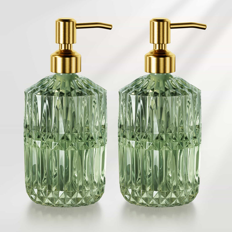 Two green glass soap dispensers with gold pumps on a white background