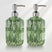 Two green glass soap dispensers with metallic pumps on a white background