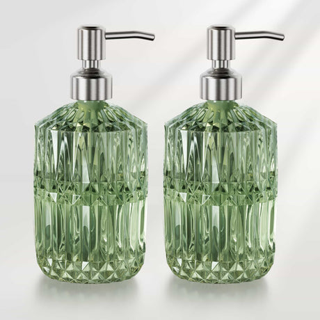 Two green glass soap dispensers with metallic pumps on a white background