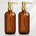 Two brown bottles with gold pumps on a white background