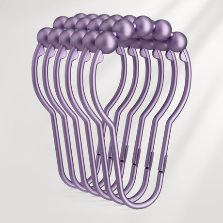 Set of purple shower curtain hooks on a light gray background