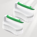 Two white cleaning brushes with green handles on a light gray background