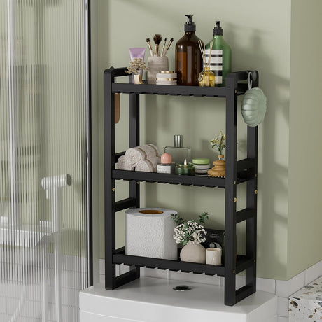 AmazerBath black bamboo three-tier toilet rack holding toiletries, towels and tissue boxes.