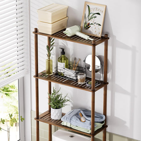 AmazerBath walnut brown bamboo over-the-toilet storage shelf organized with towels, toiletries, and decor.