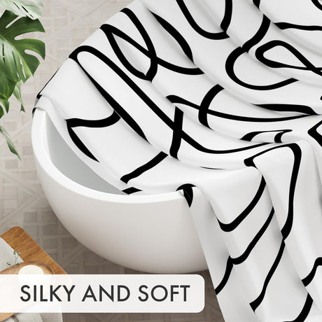 Close-up of the soft black abstract AmazerBath shower curtain fabric draped over a bathtub.