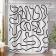 Black abstract line-art AmazerBath shower curtain fully installed over a white bathtub.