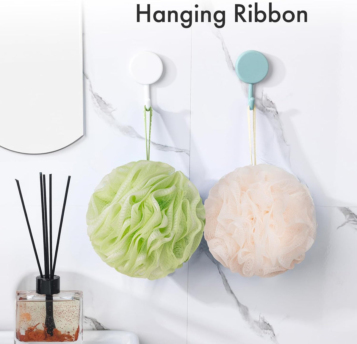 AmazerBath melon and green charcoal loofah sponges hanging from their ribbons on bathroom wall hooks.