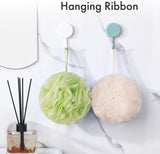 AmazerBath melon and green charcoal loofah sponges hanging from their ribbons on bathroom wall hooks.