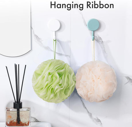 AmazerBath melon and green charcoal loofah sponges hanging from their ribbons on bathroom wall hooks.