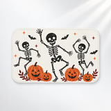 Dancing skeleton Halloween bath mat with playful orange pumpkins on a light gray background