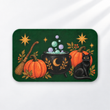 Witchy black cat Halloween bath mat with a cauldron and pumpkins on a light gray background