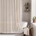 AmazerBath beige grid linen shower curtain: a grid curtain with white tassel trim hangs beside a bathtub in a bright bathroom.