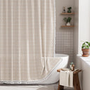 AmazerBath beige grid linen shower curtain: a grid curtain with white tassel trim hangs beside a bathtub in a bright bathroom.