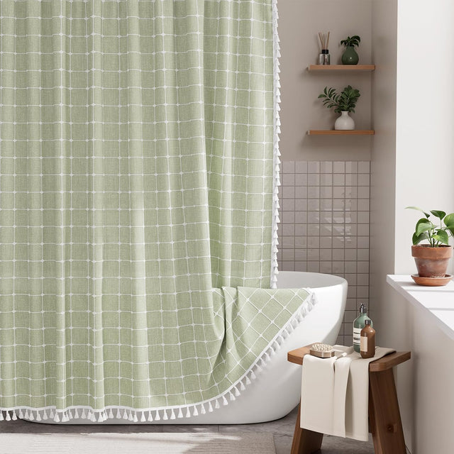 AmazerBath sage green grid linen curtain: a grid curtain with white tassel trim hangs beside a bathtub in a bright bathroom.