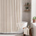 AmazerBath beige striped linen curtain: striped fabric and white tassel trim frame a bathtub in a bright bathroom.