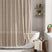 AmazerBath taupe striped linen curtain: textured fabric and white tassel trim frame a bathtub in a bright, neutral bathroom.