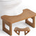 AmazerBath dark wood foldable toilet stool: the compact folding stool rests in front of a toilet with its support legs visible.
