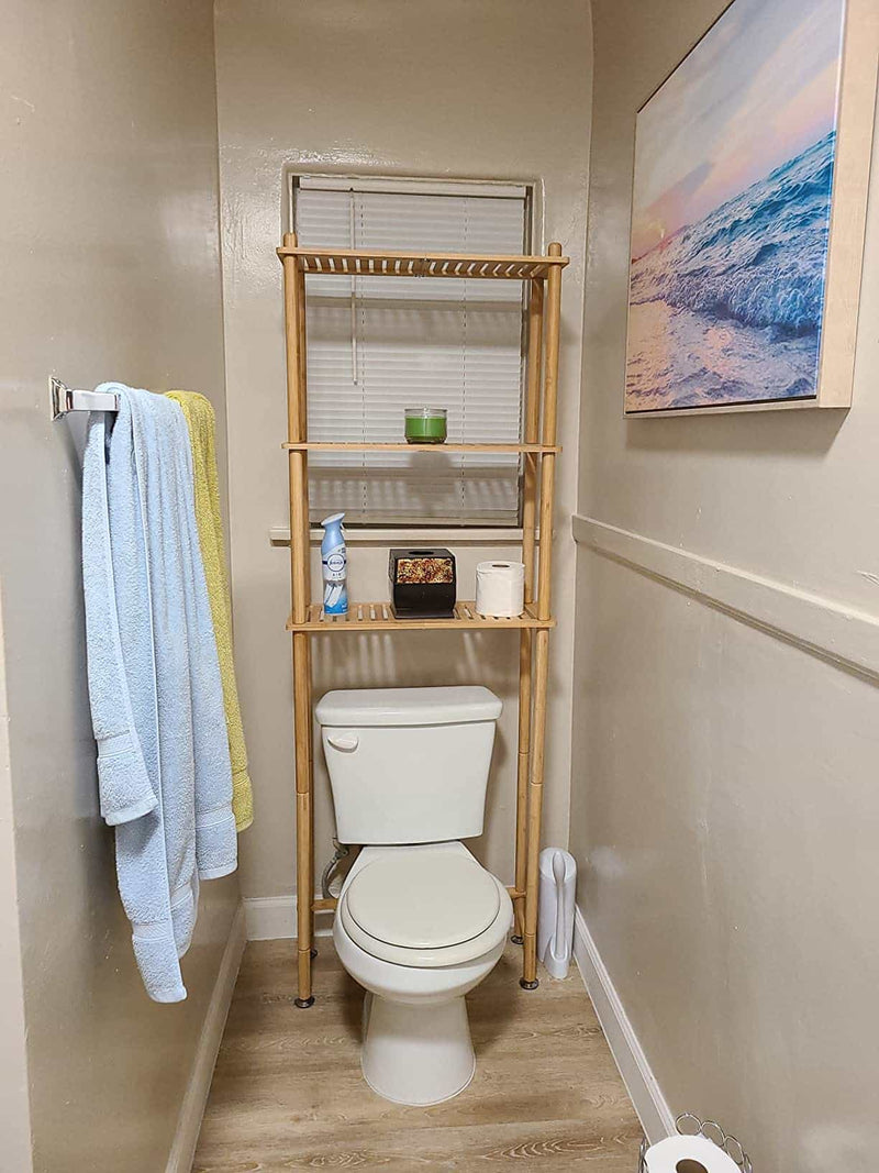Bathroom with a toilet, over-the-toilet shelf, and towels hanging on a rack.