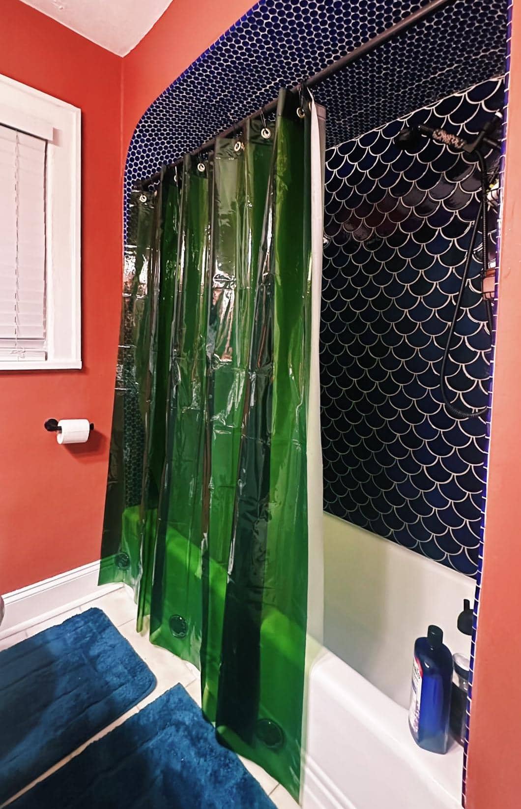 Green and navy rainbow shower curtain in a red bathroom
