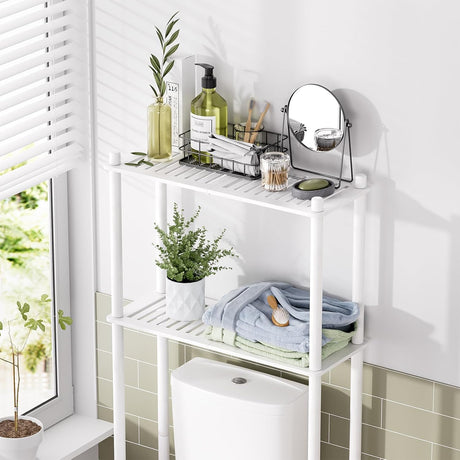 AmazerBath White bamboo two-tier over-the-toilet shelf holding toiletries, folded towels, a mirror, and a plant above a toilet.