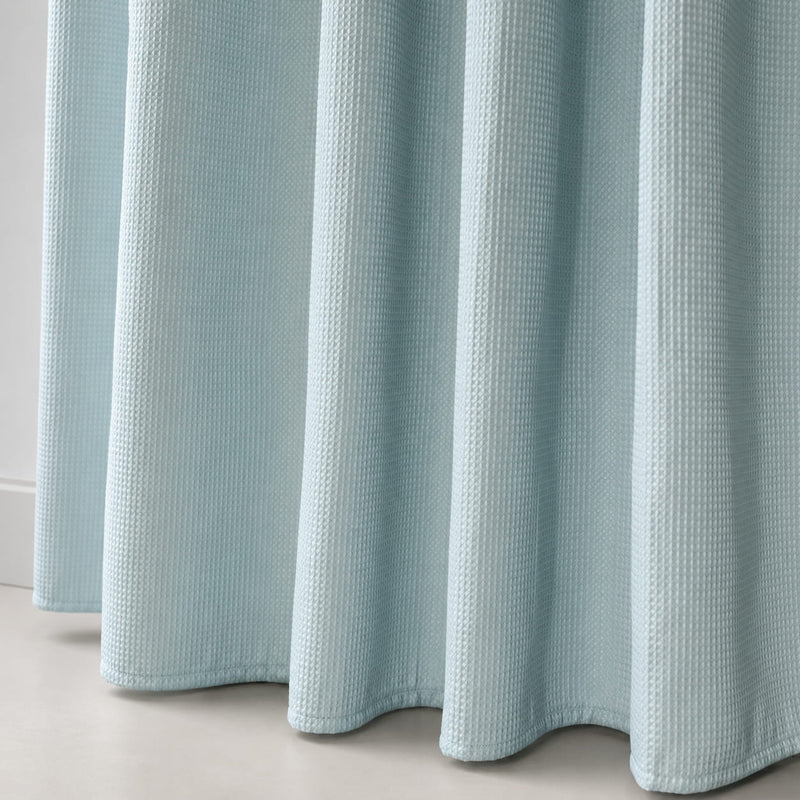 Light blue textured shower curtain on a neutral background